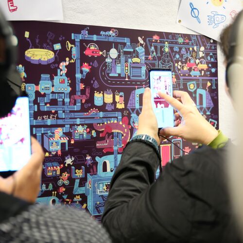 Users in front of the hidden objects picture using the AR app